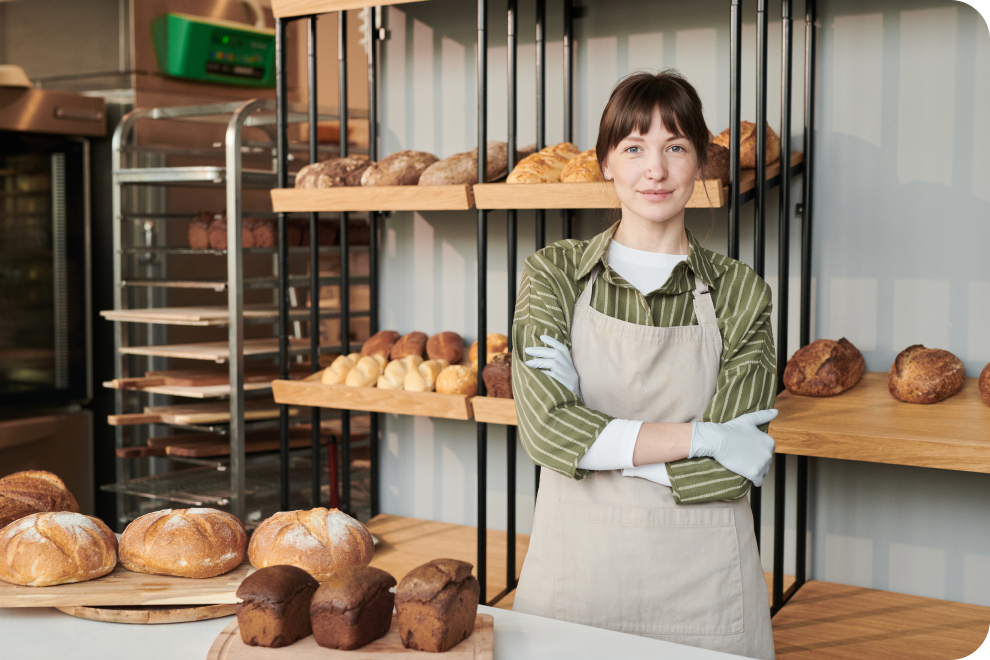 A female employee wearing an apron is standing in the bakery section.