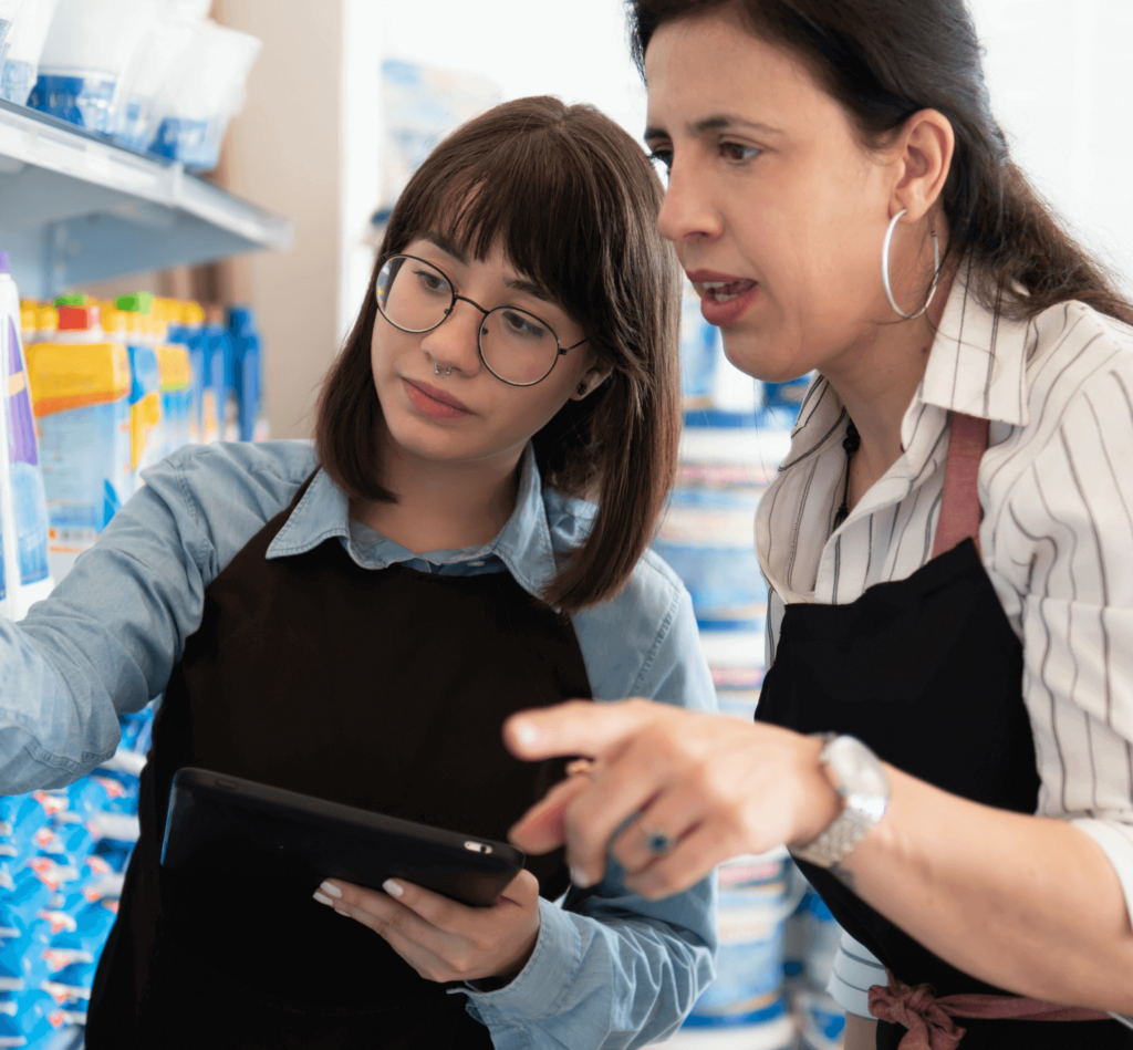 A female employee holding a tablet is standing with her female co-worker to check the inventory in a grocery store.