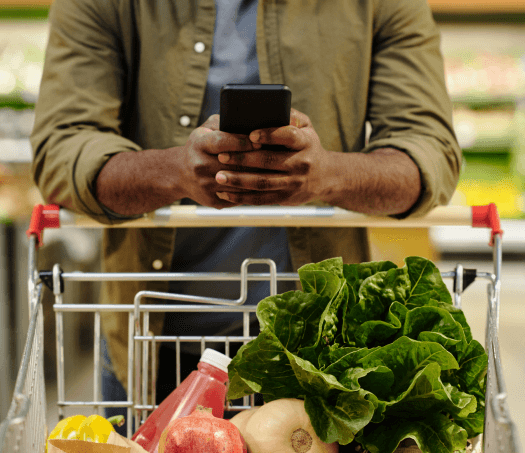 A customer is using the Modisoft application on his mobile while shopping for groceries in the grocery store.