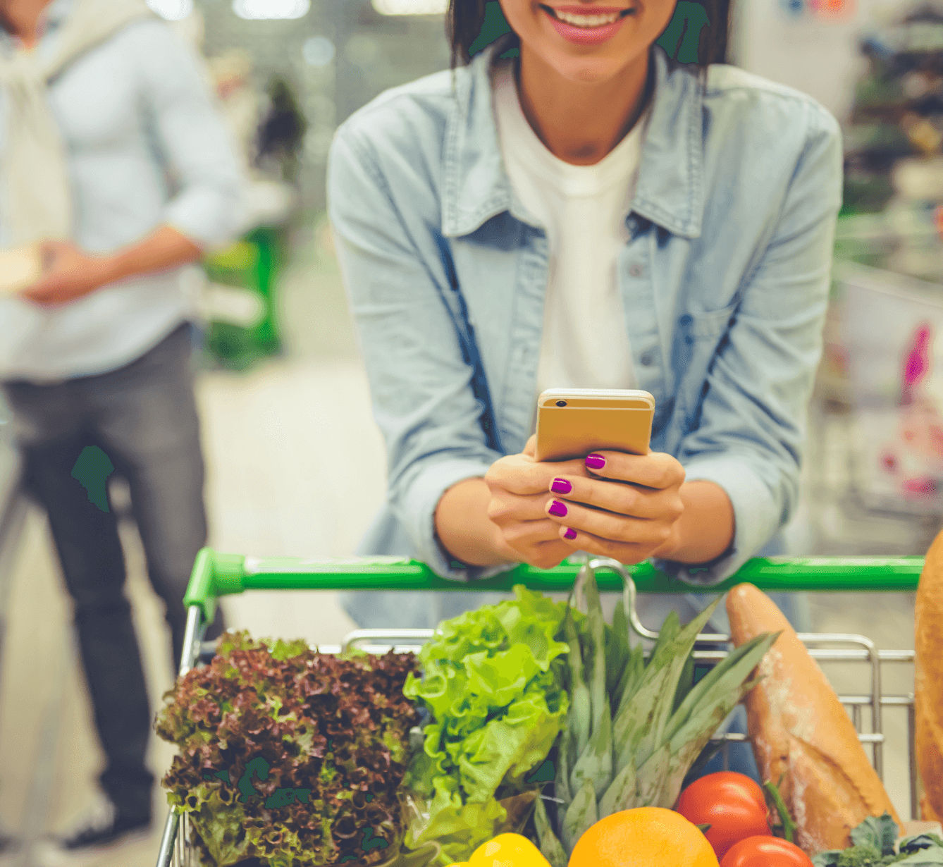 A woman with a trolly full of groceries is standing in the grocery store and using Modisoft loyalty reward on her mobile.