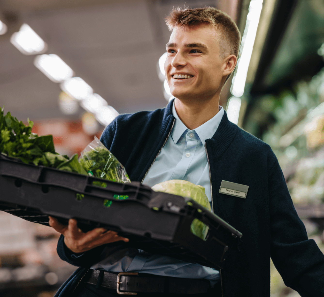 A grocery store employee is holding a vegetable container.