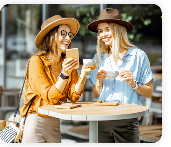 Two women sitting in the cafe are holding a cup of coffee.