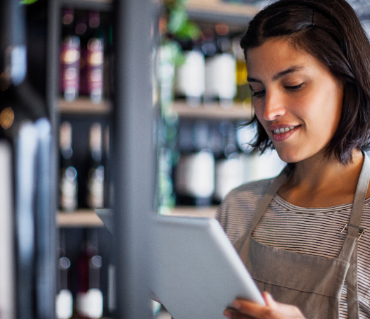 A female employee of a Liquor store is using Modisoft Multi-Location Management system software on a tablet.