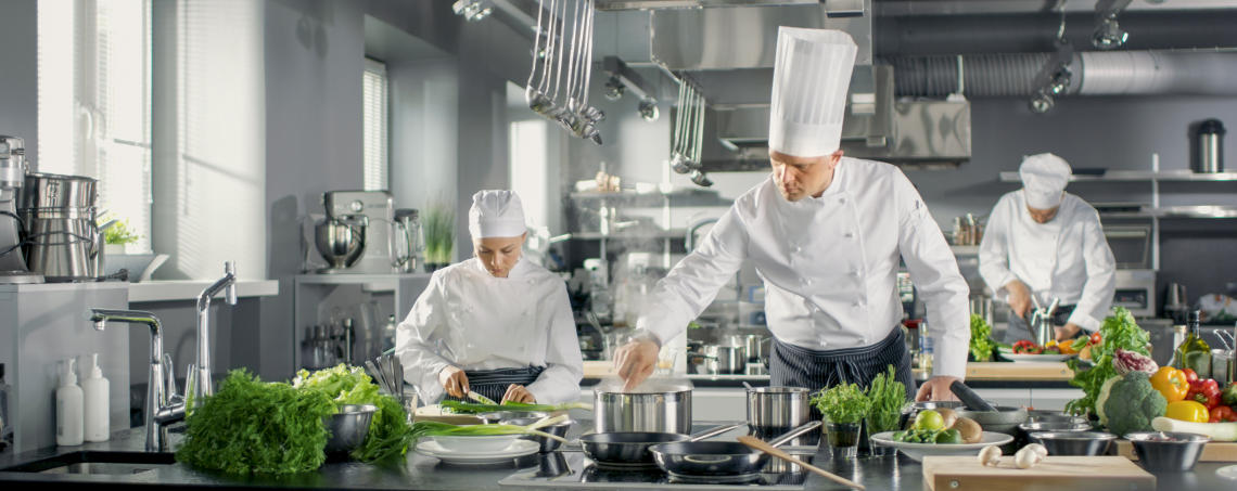 Chefs standing in the kitchen are preparing food.
