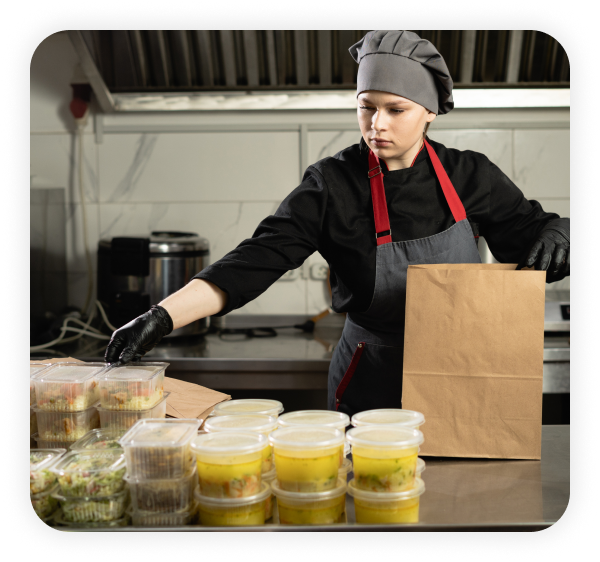 A female chef is packing orders in the kitchen.