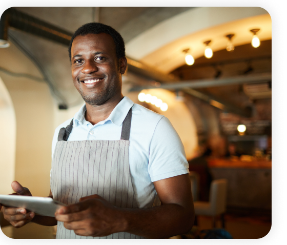 A male employee standing in the restaurant is holding a tablet.