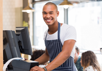 A young and happy male employee is using the Modisoft POS system.