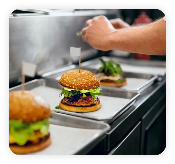 Chef dressing burgers in the kitchen.