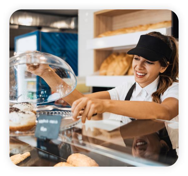 Young and happy female worker working in the bakery.