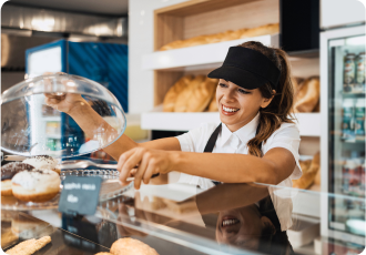 A young and happy female employee is working in the bakery.