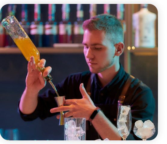 A bartender standing in the bar is preparing juice.