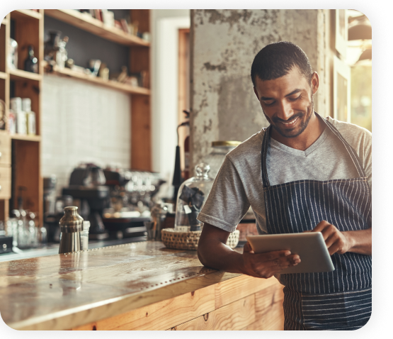 An employee wearing an apron is holding a tablet.
