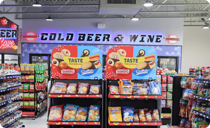Mak's Convenience store interior featuring product aisles, snack displays, beverage coolers, and illuminated Cold Beer & Wine signage.