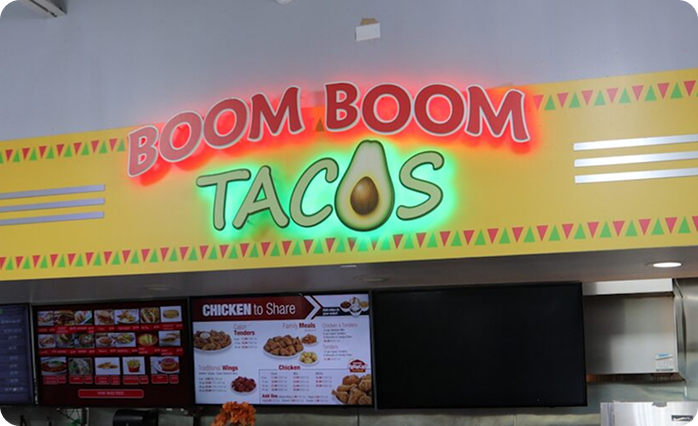 Boom Boom Tacos food service area featuring illuminated signage, digital menu boards, and food ordering displays.