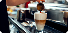 Coffee beverage being prepared from an espresso machine into a glass cup.