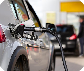 Fuel pump dispensing fuel into a vehicle at a gas station forecourt.