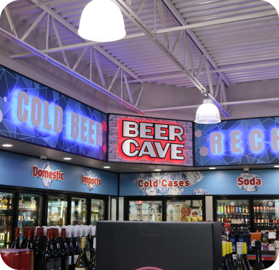 Convenience store interior featuring beverage coolers, product displays, and illuminated Beer Cave signage.