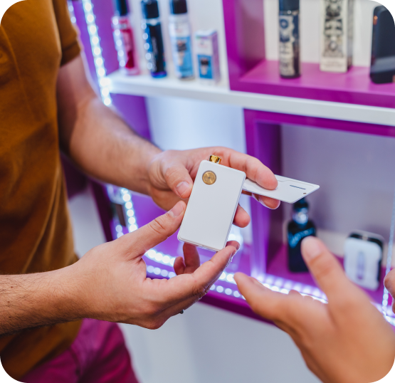Retail customer viewing vape devices and accessories in front of illuminated smoke shop product displays.