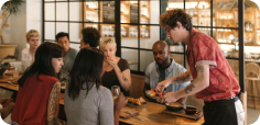 Group of customers gathered around a table sharing food and beverages in a casual dining setting.